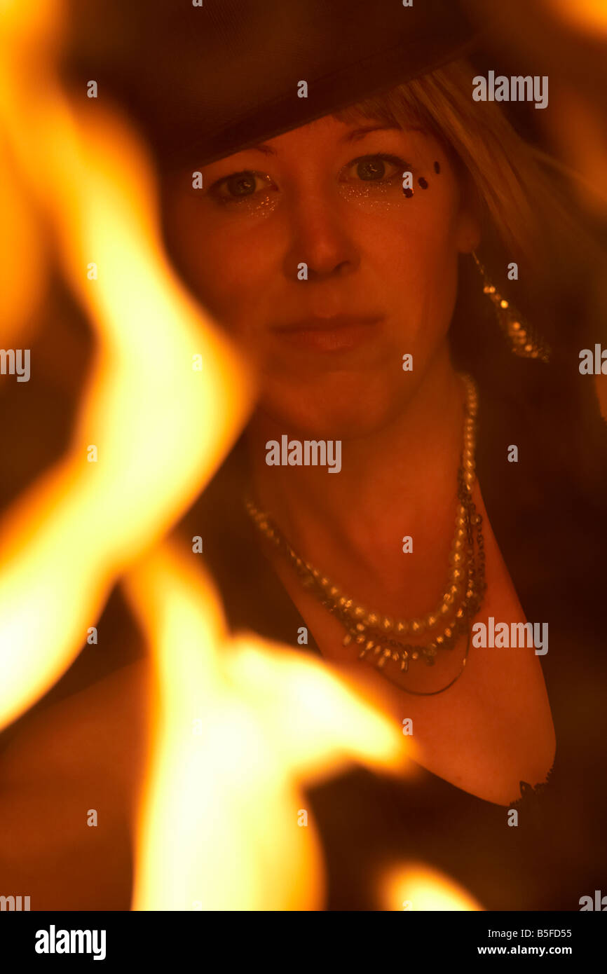 firepoise female fire dance performance artist wearing hat holding fire