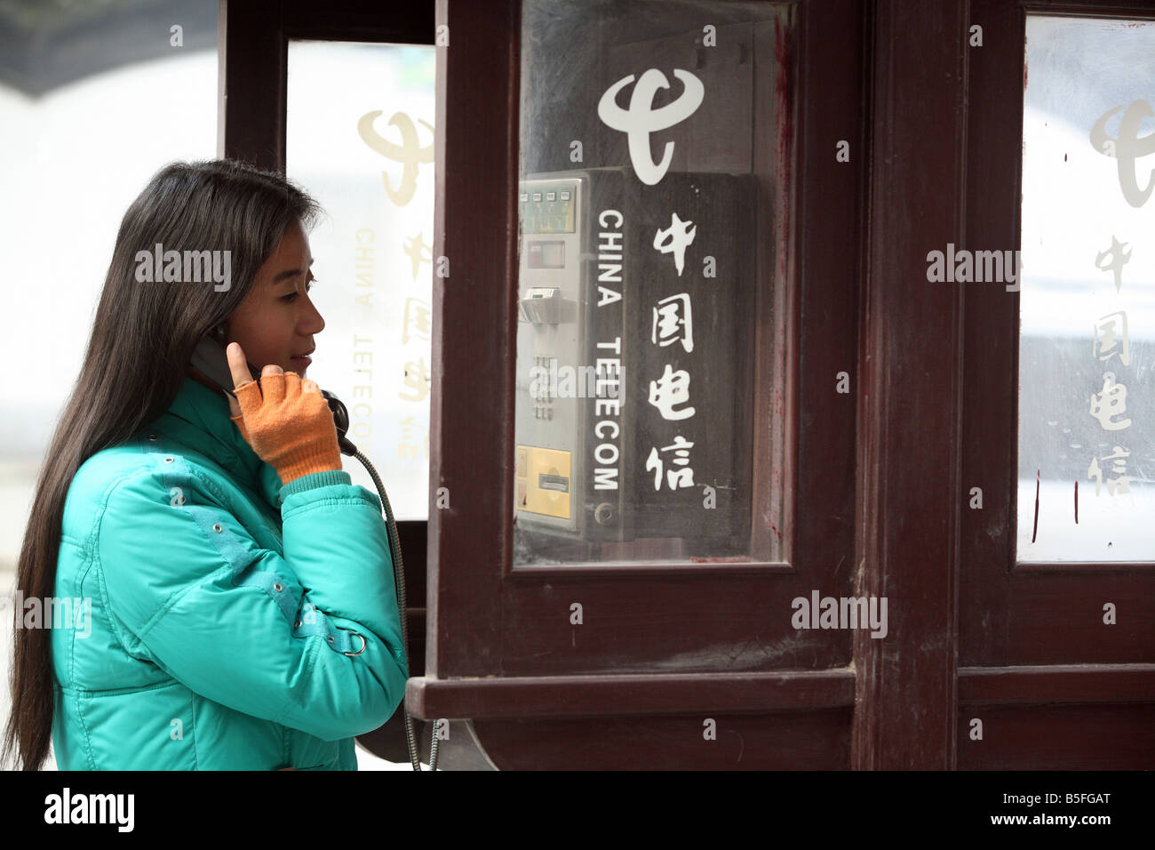 A young Asian woman at a public phone booth, Suzhou, China Stock Photo