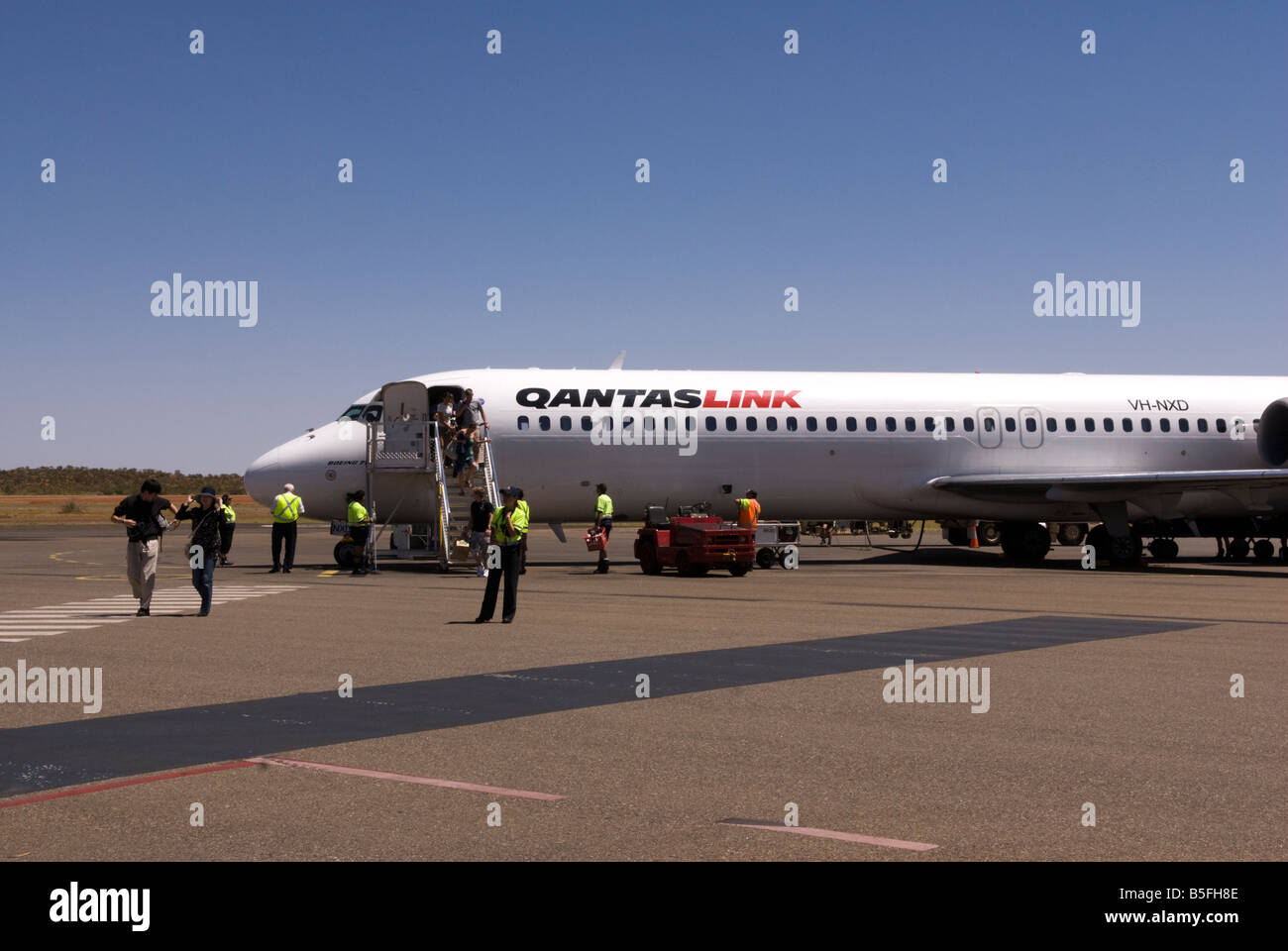 Passengers disembark an aeroplane at Uluru Ayer's Rock airport, Australia and walk across to the terminal Stock Photo