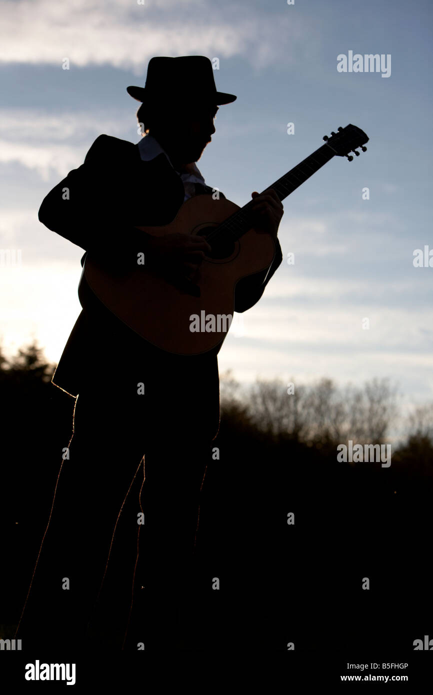 bearded 20s man playing guitar outdoors Stock Photo