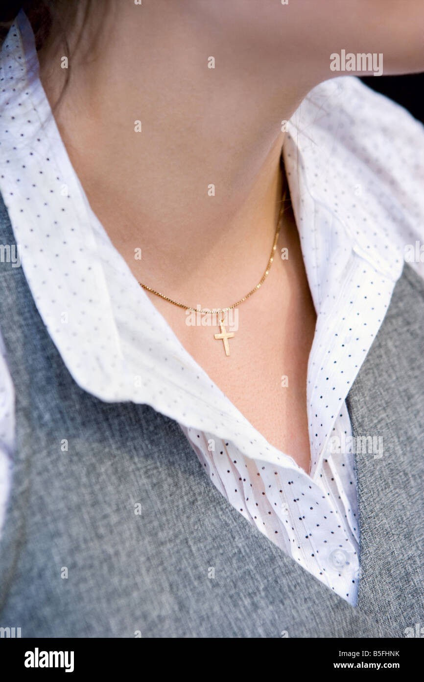 The throat of a young woman wearing a gold crucifix. Stock Photo