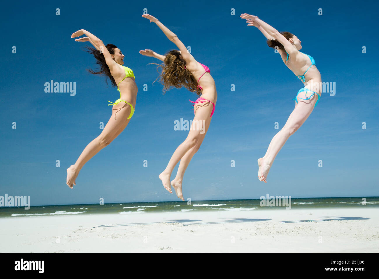 women in bikini jumping on beach Stock Photo Alamy