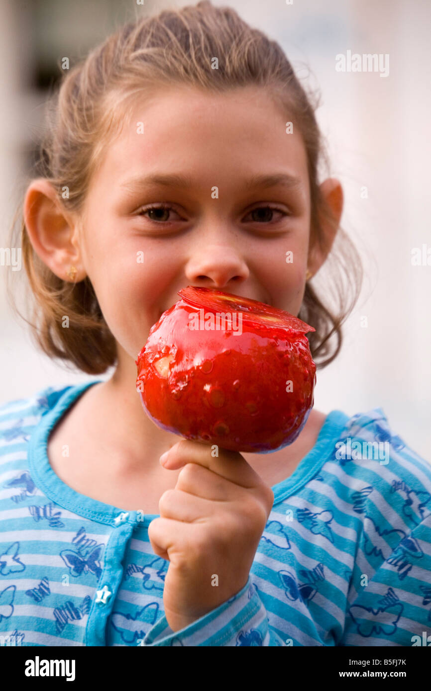 A young girl smiles as she is about to eat a candied apple. Stock Photo