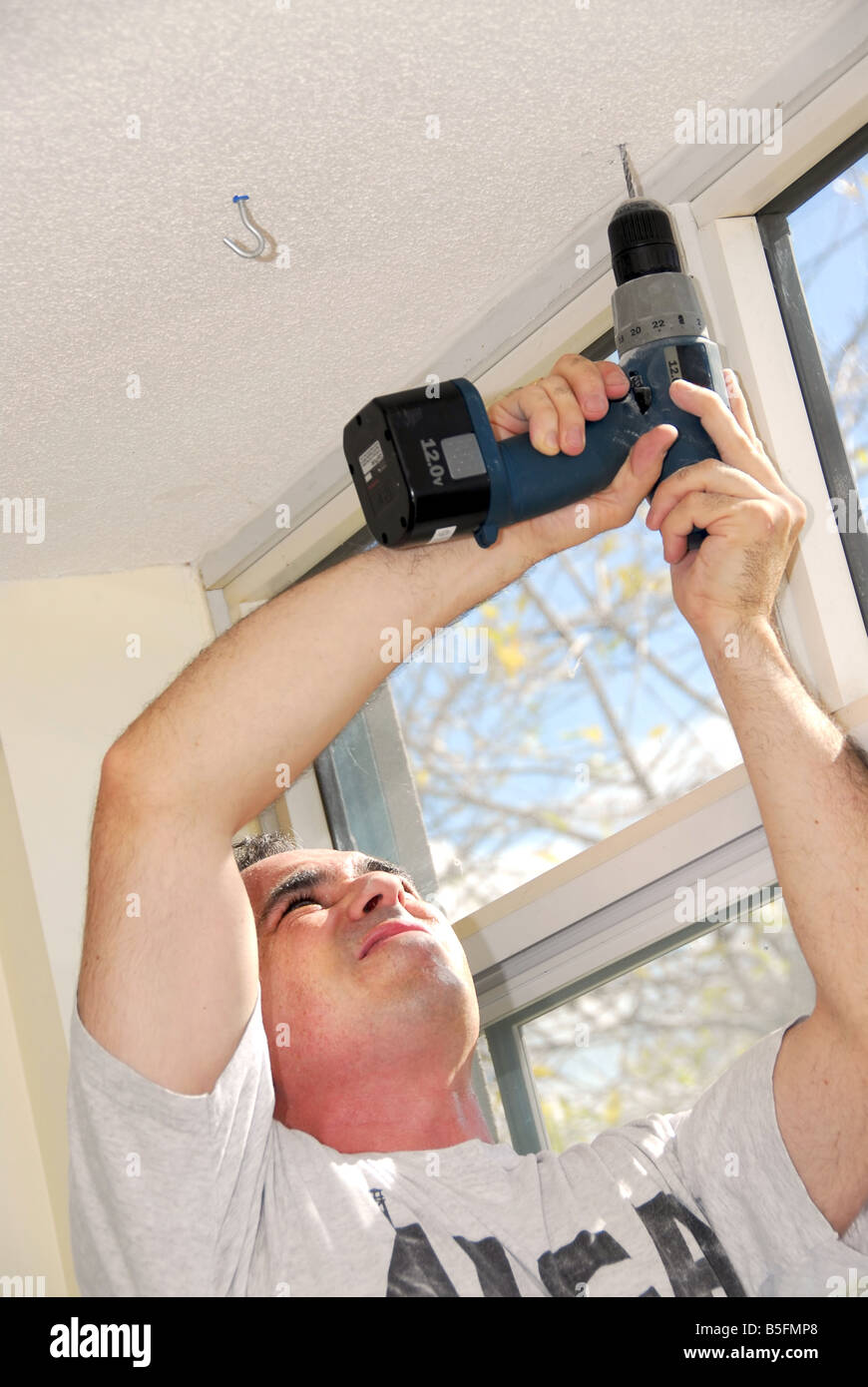 Man drilling a hole in a ceiling Stock Photo