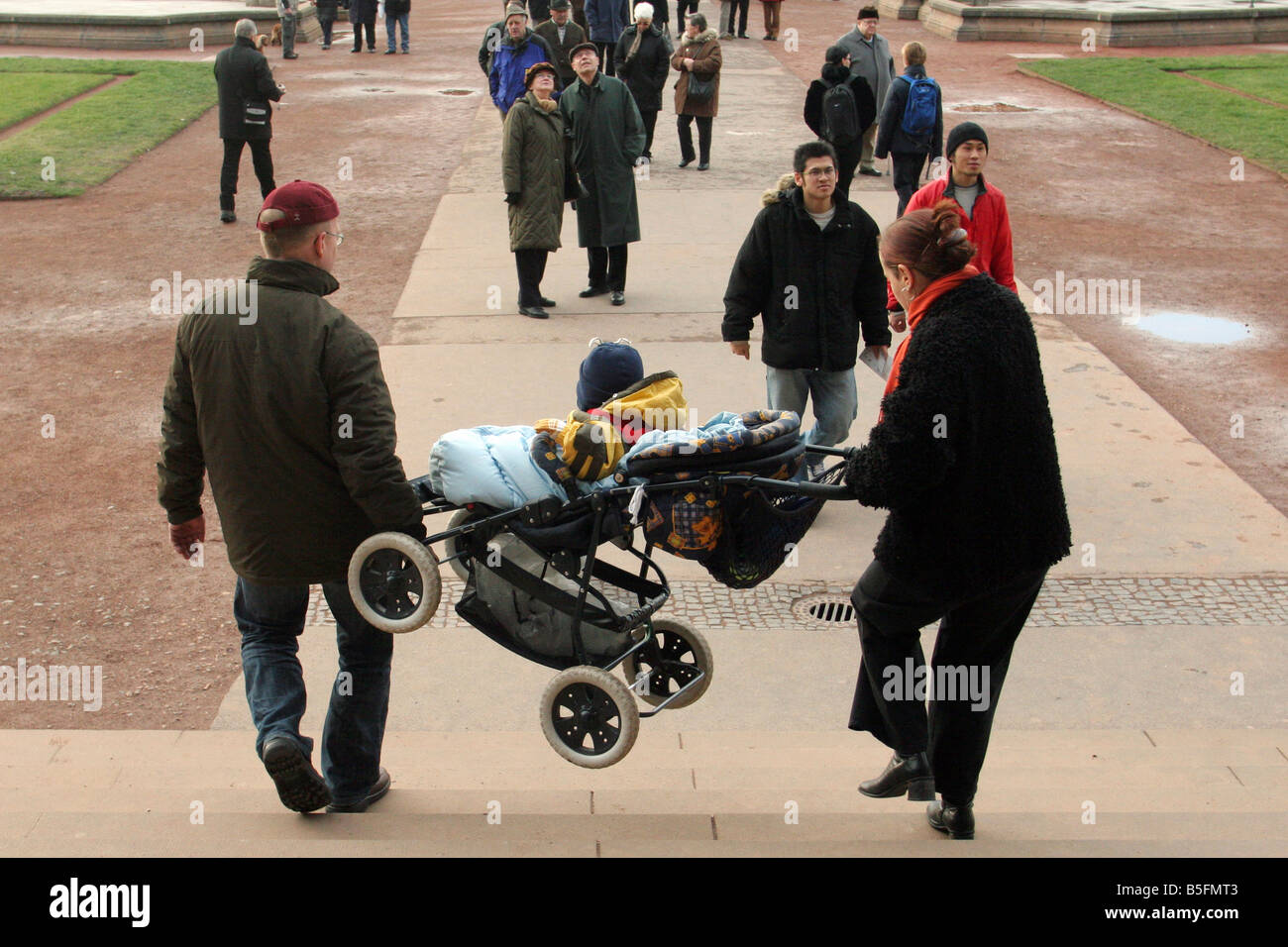 Parents carrying a pushchair downstairs, Dresden, Germany Stock Photo
