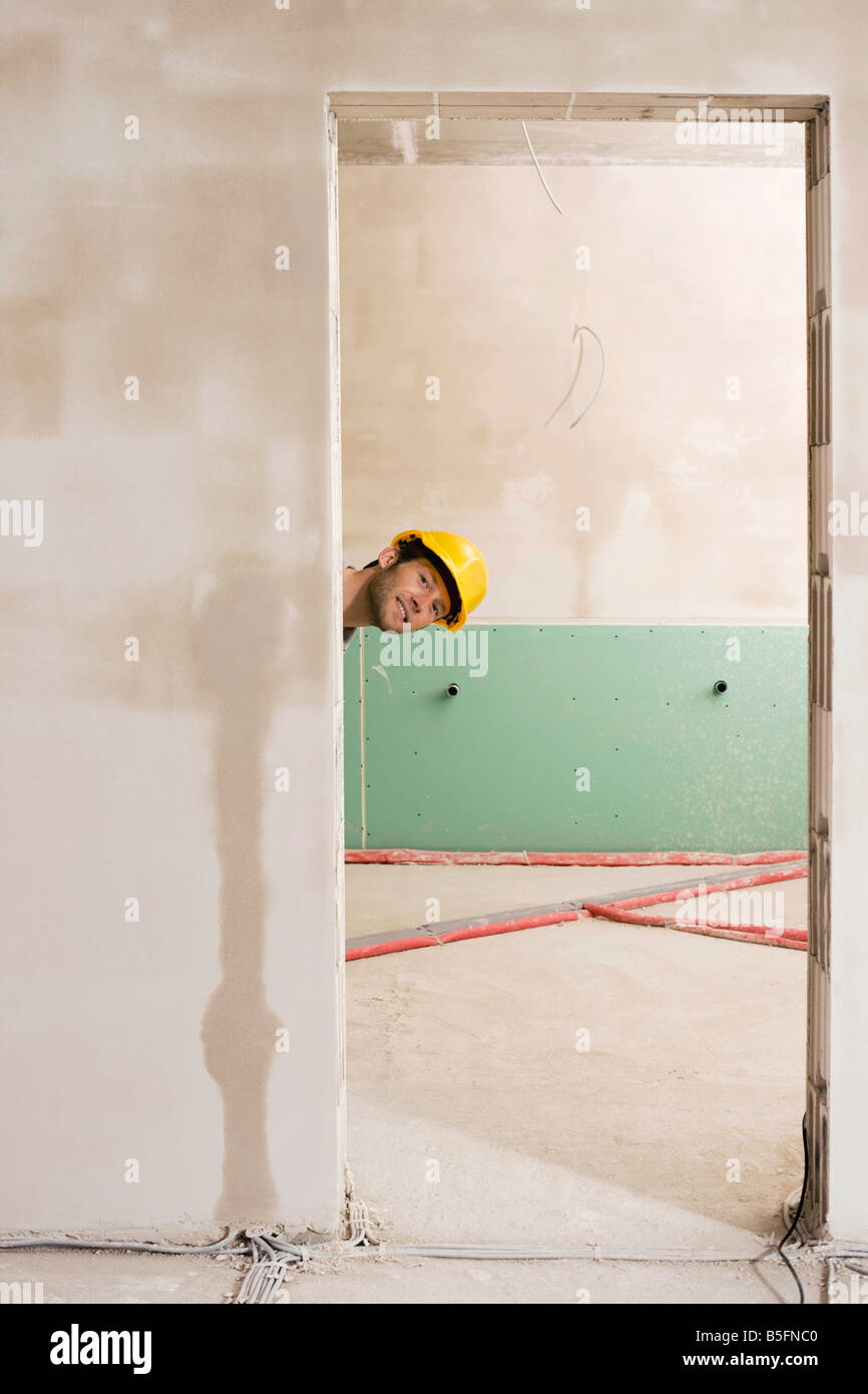 Construction worker peering through door Stock Photo