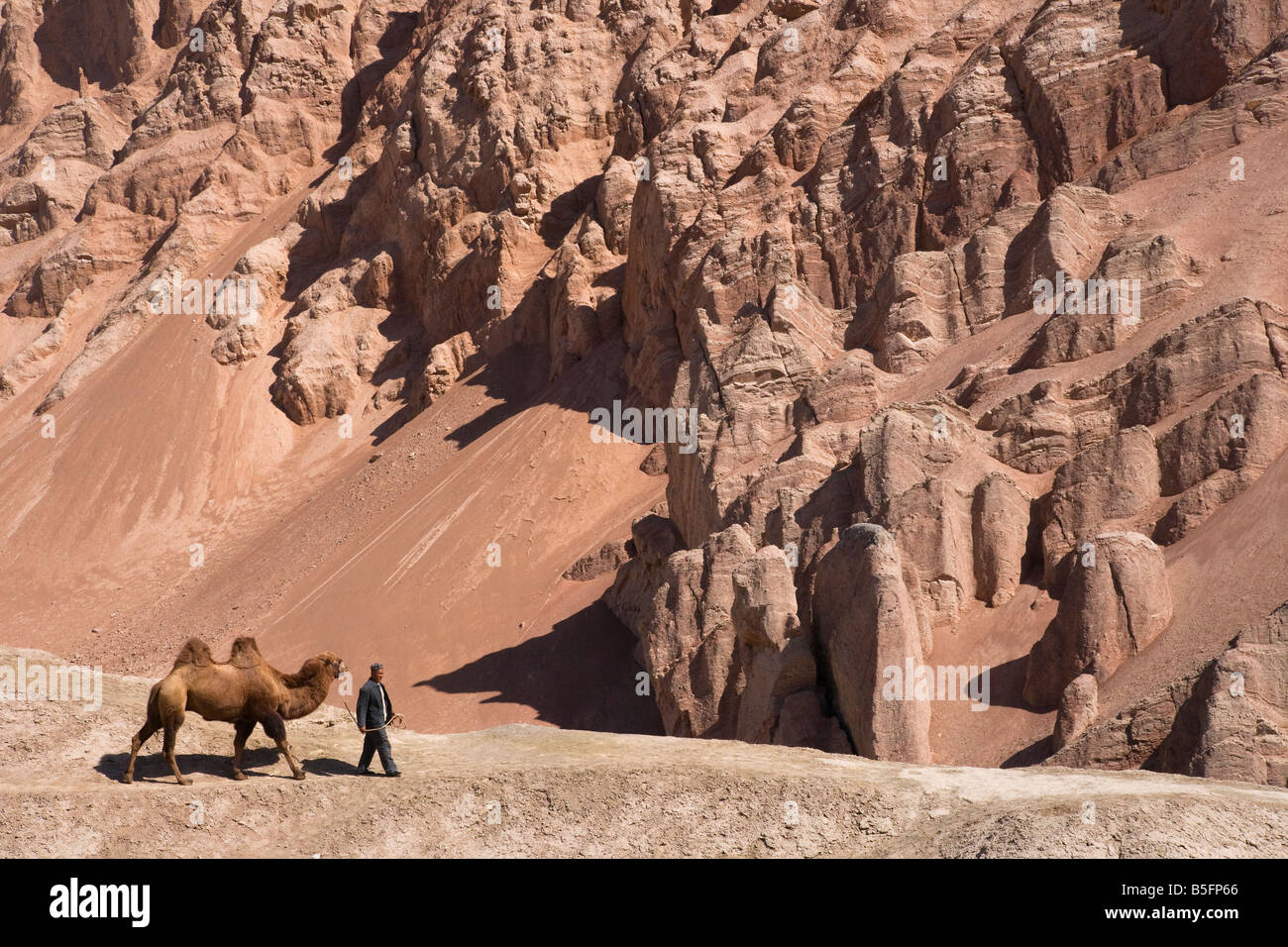 Man with camel in eroded valley Turpan Xinjiang Province Silk Road China Stock Photo