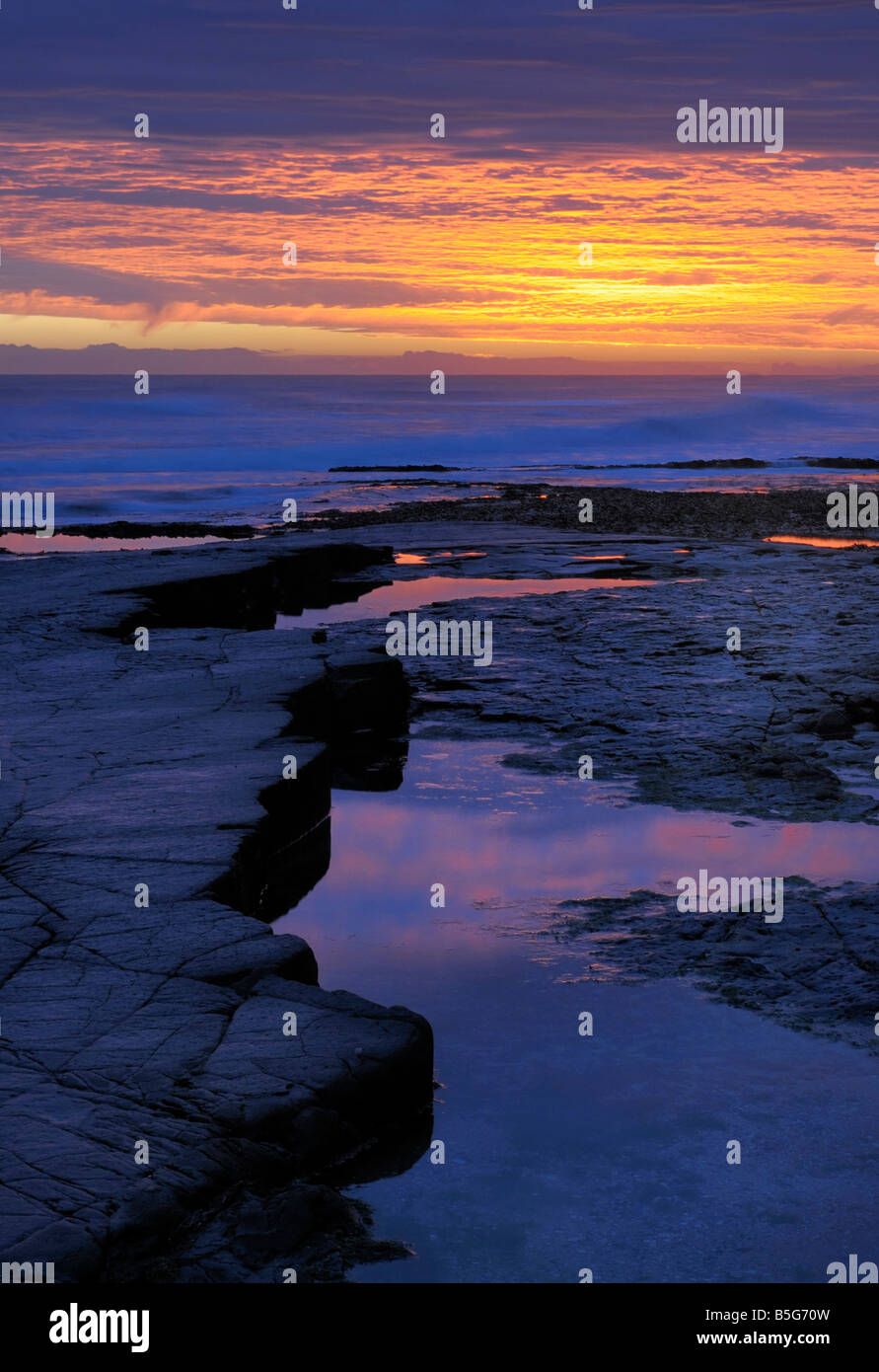 Sunrise and sky reflected in a rock pool Stock Photo