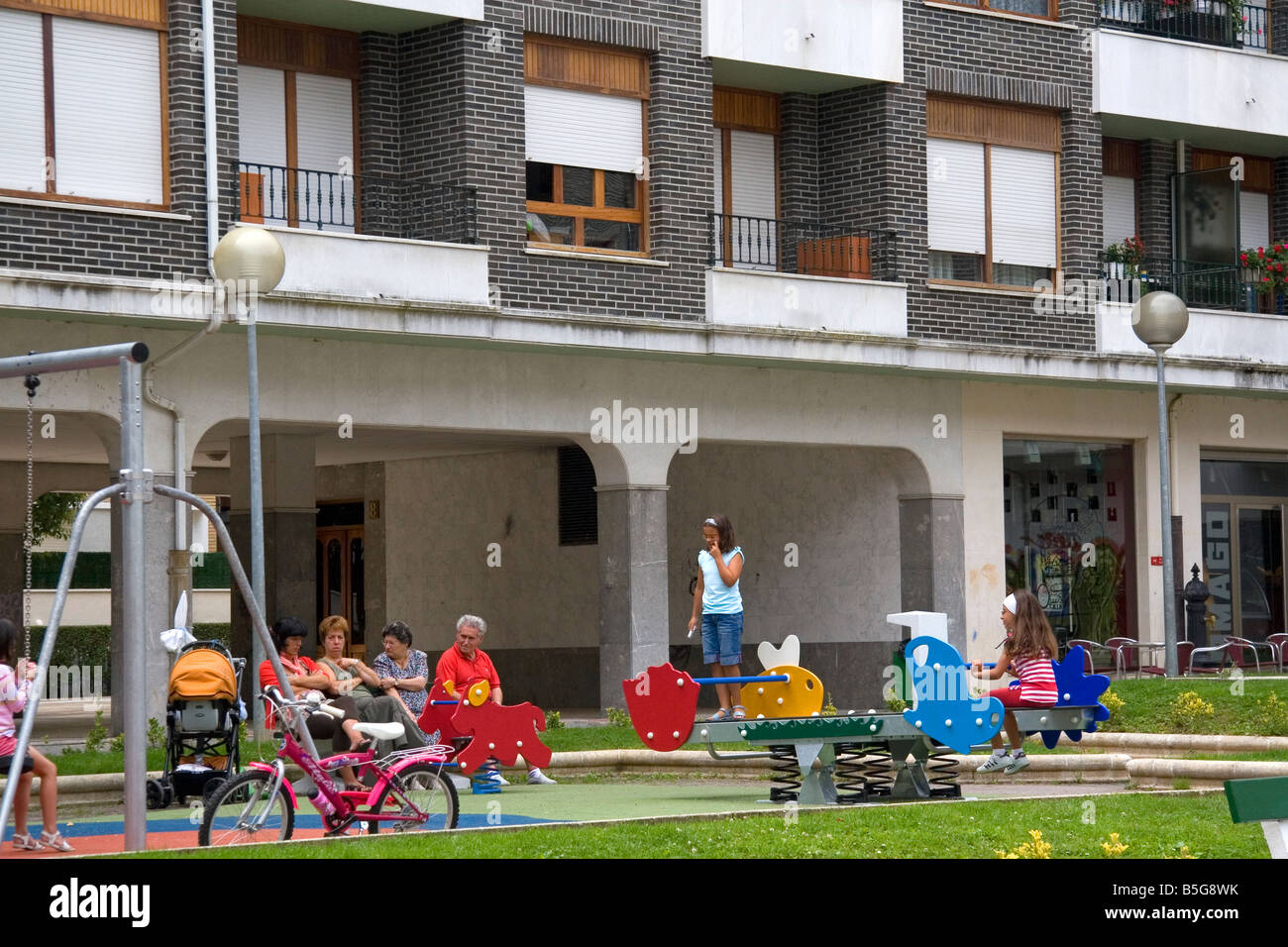 Children use playground equipment in front of an apartment housing unit in Guernica northern Spain Stock Photo