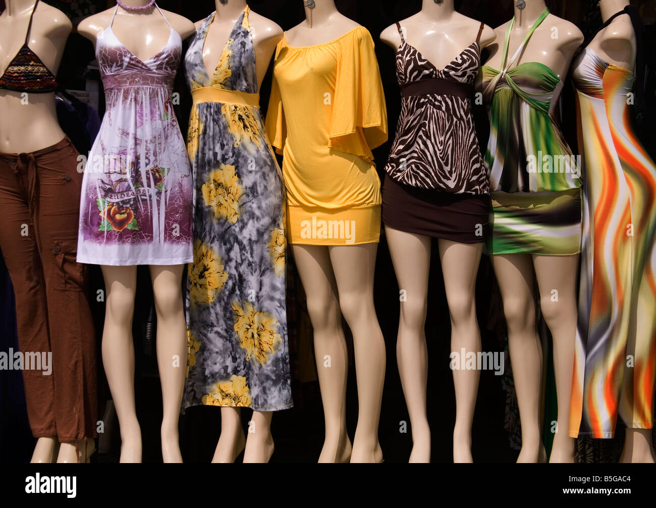 Frame filling image of a group of mannequins outside a casual clothing shop, each wearing a colorful summer outfit. Stock Photo