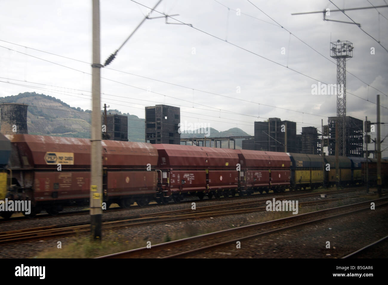 Derelict factory, Sometra, Carbosin, Copsa Mica, passing freight train,Transylvania, Romania Stock Photo