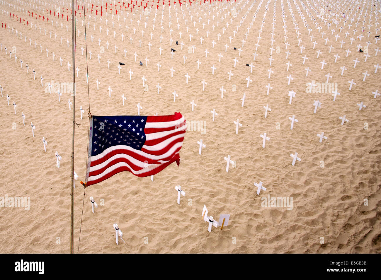 U.S. Flag at half mast over a Memorial to those who died in war Stock