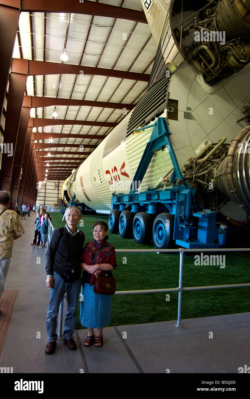 Viewers posing in front of massive Saturn V rocket used in the Apollo space missions to the moon Stock Photo