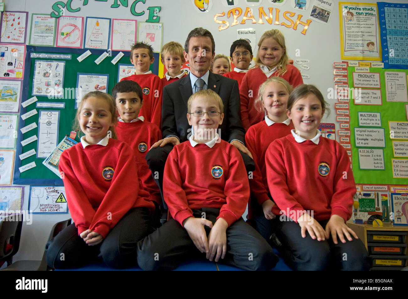 A primary school headmaster with pupils in red uniform sweatshirts in a classroom Stock Photo