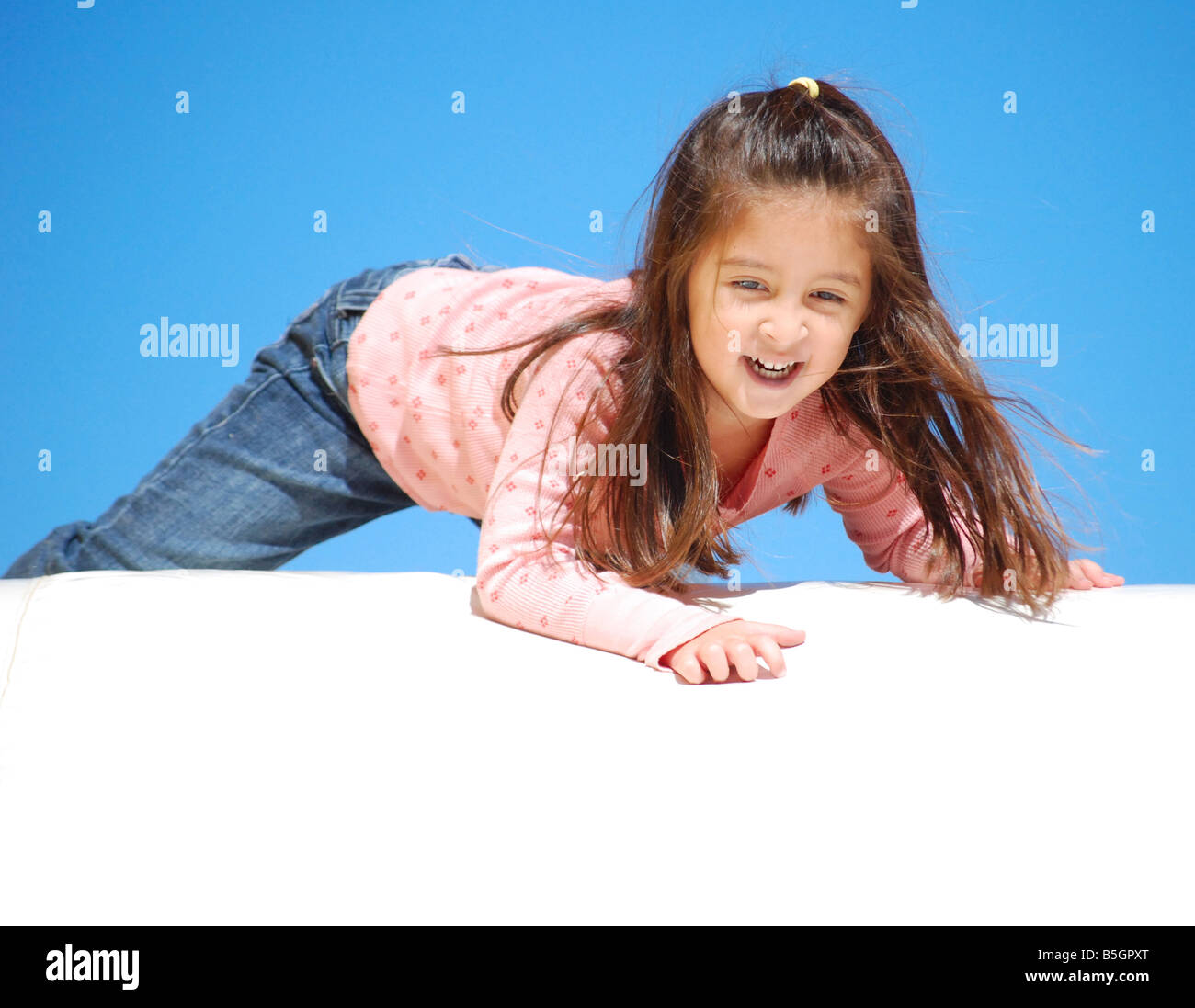 Young Mexican gril getting ready to slide down a slide Stock Photo