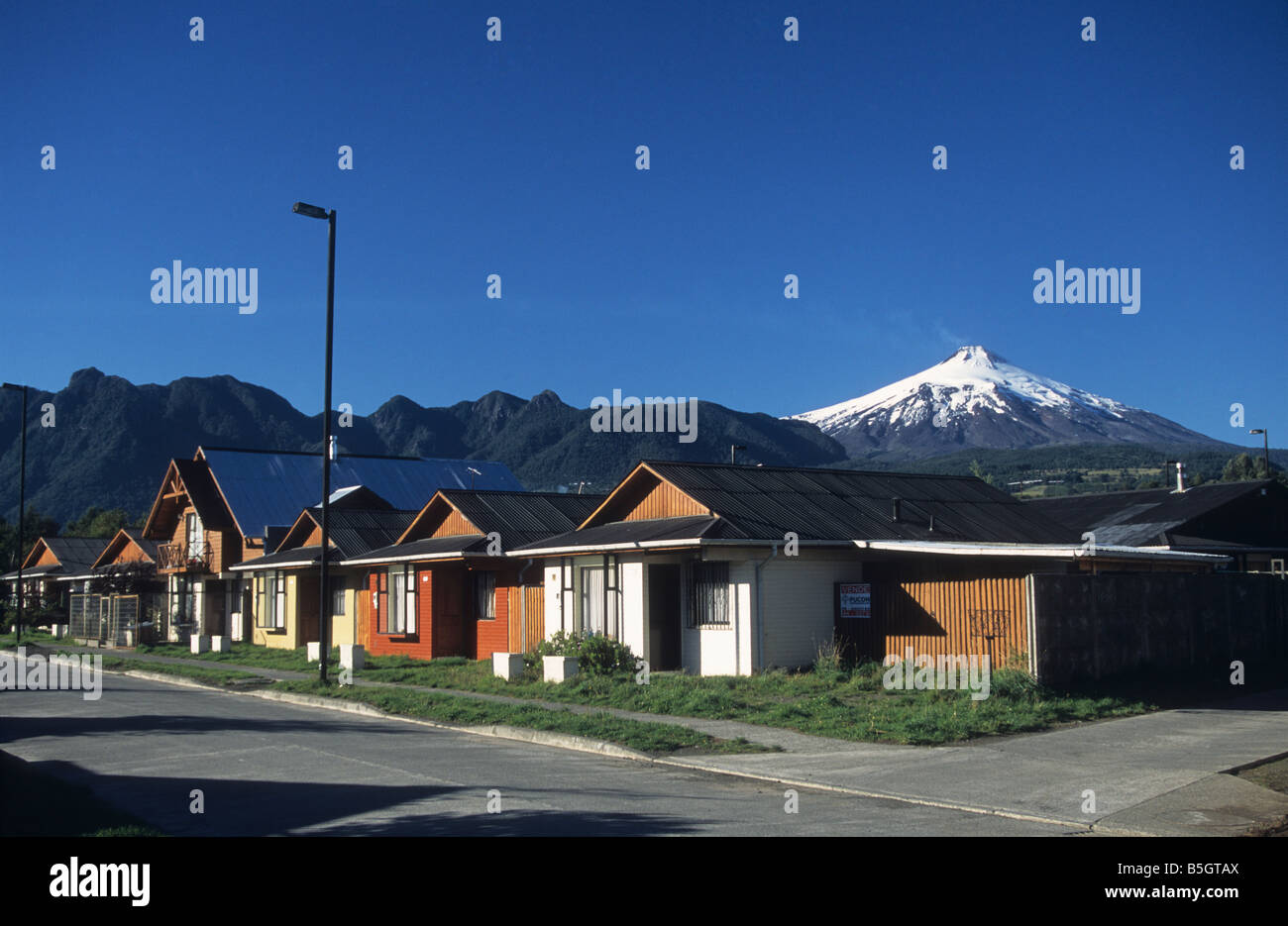 Wooden houses in residential suburb of Pucon, Villarrica volcano in background, Region de La