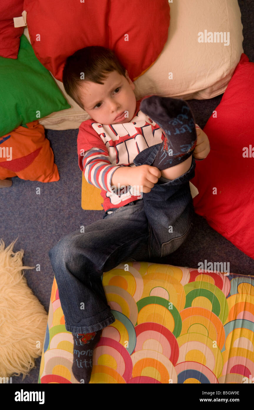 young boy child in nursery day care centre boy pulling on his socks