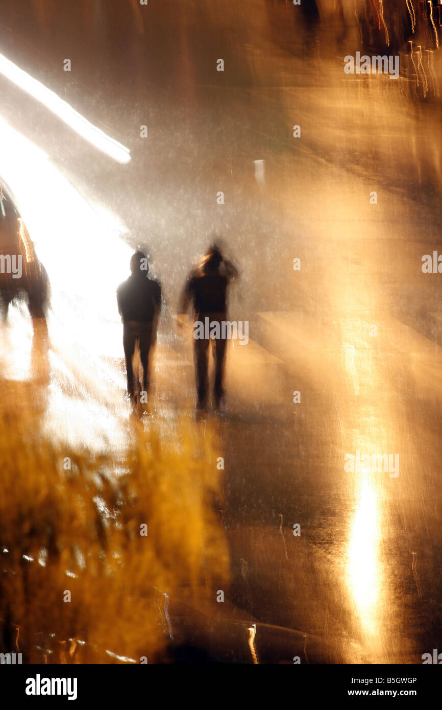 two people walking in heavy rain at night in town Stock Photo