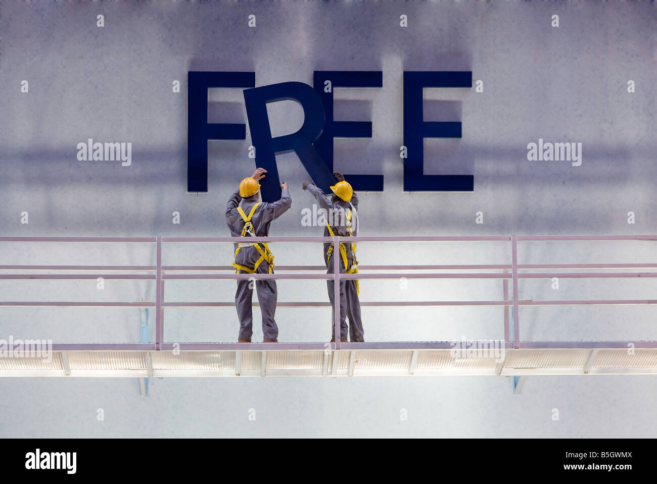 Workers preparing a billboard with the word free while standing on a scaffold Stock Photo