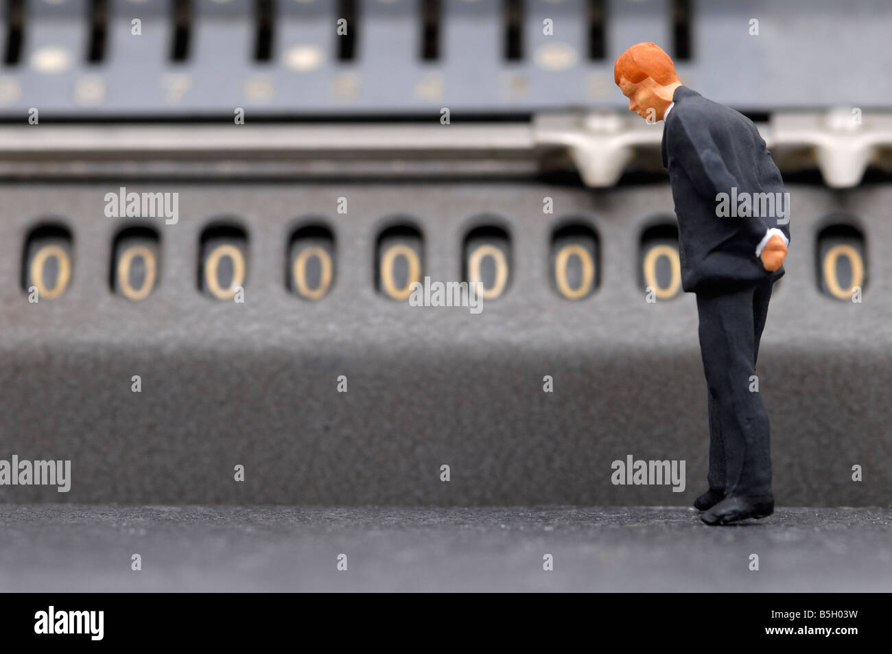 figure of a business man in front of a calculating machine, symbol of insolvency Stock Photo