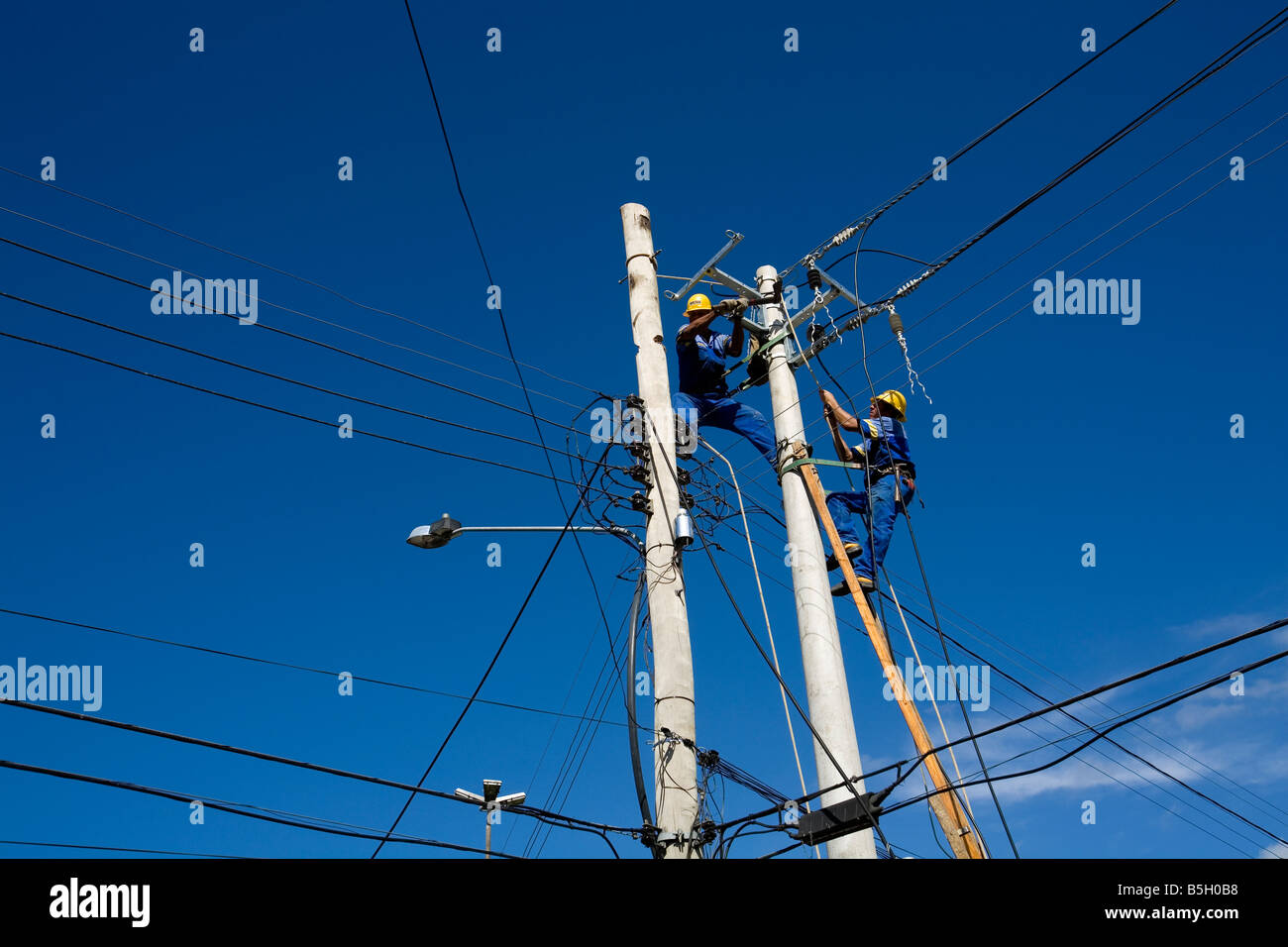 A man is cutting down an electricity post with an axe Paraty Rio de Janeiro state Brazil Stock Photo