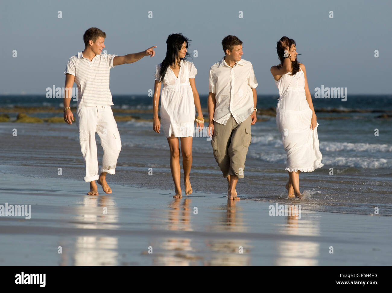 Four people walking on a beach hi-res stock photography and images - Alamy
