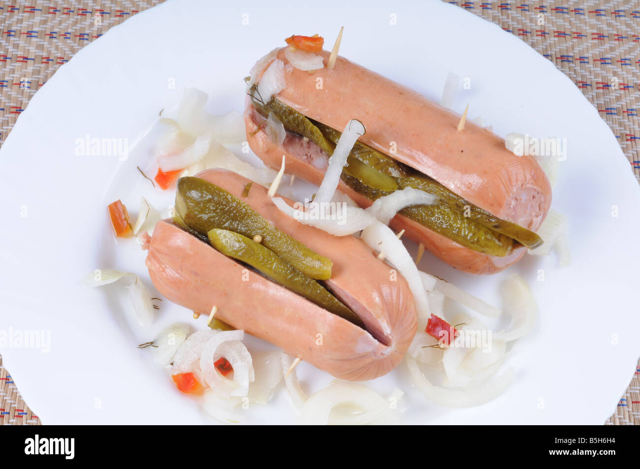 Pickled sausages with sliced onion and cucumber on white plate.Traditional Czech food. Stock Photo