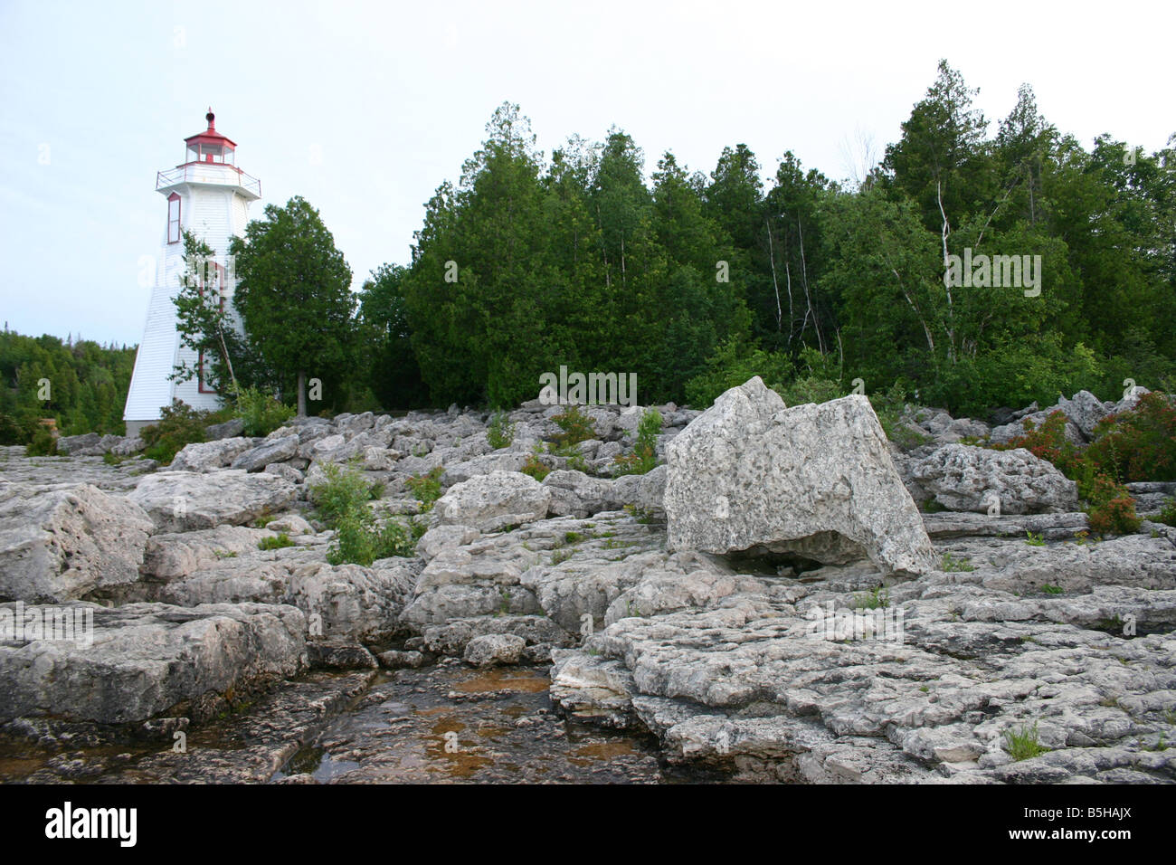 Huge boulders sit at the foot of historic, wooden Big Tub lighthouse, on the rocky shorelone of Georgian Bay, in Ontario. Stock Photo