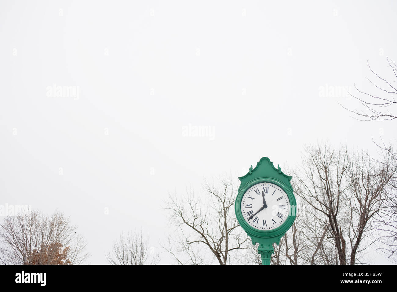 A unique green clock outdoors with Roman numerals as numbers Stock