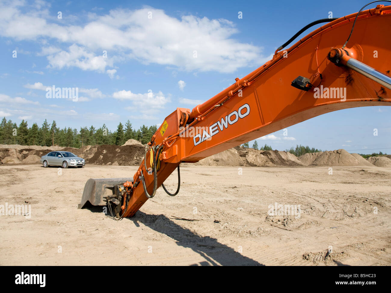 Orange Daewoo digger boom extended and Toyota Avensis car , Finland Stock Photo