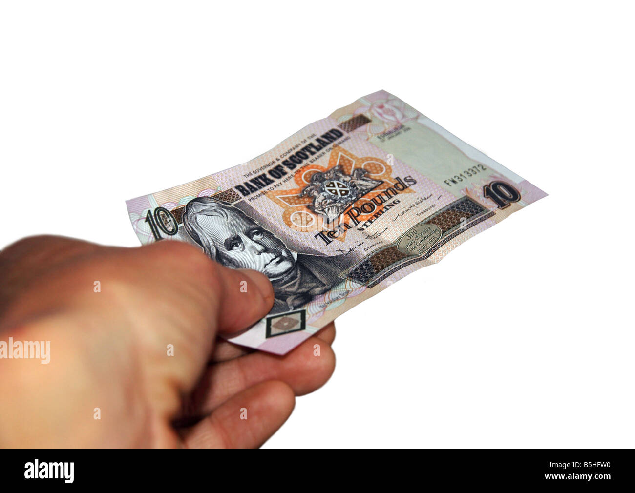 A hand giving out a Scottish ten pound note. Stock Photo