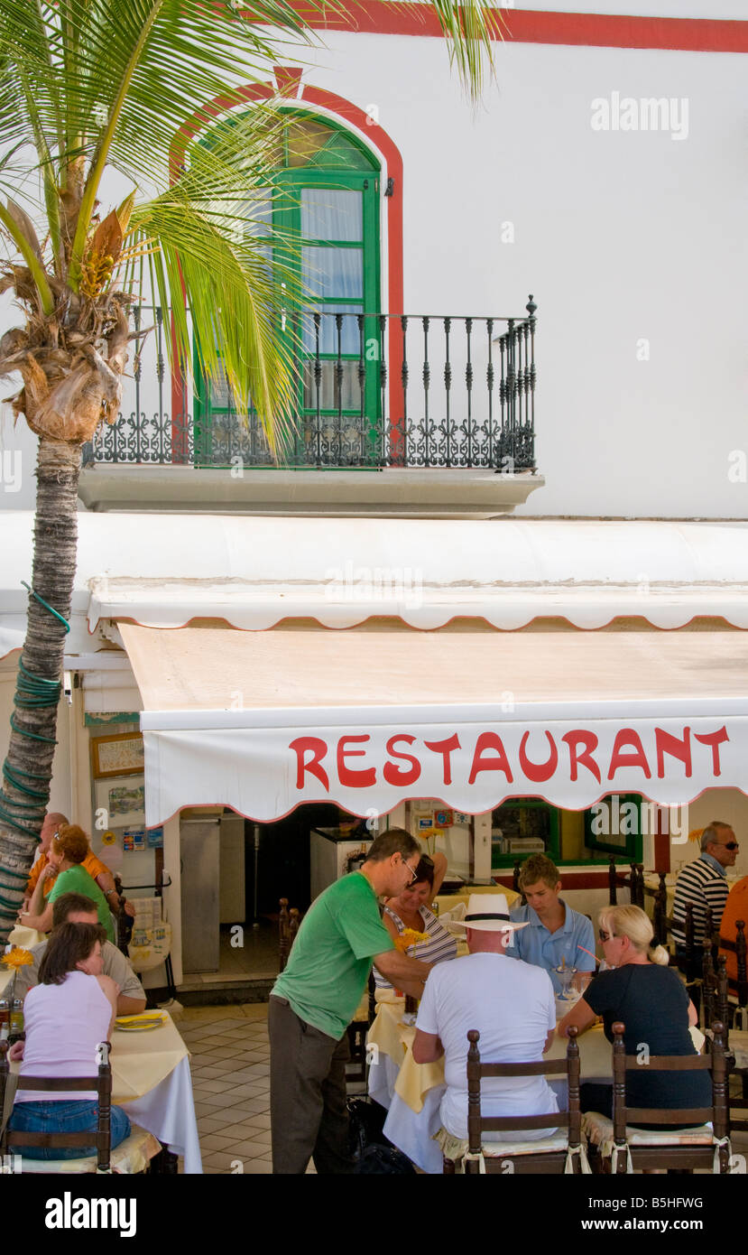 Alfresco Puerto Morgan Waiter serving typical Canary lunch to tourists in marina restaurant Puerto de Mogan resort, Gran Canaria Canary Islands Stock Photo