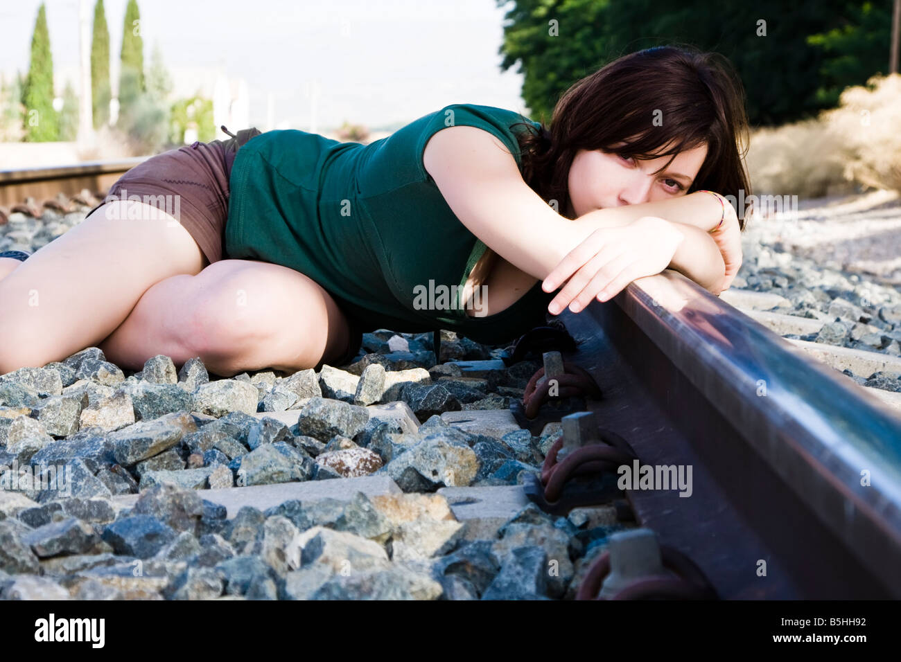 Sad young woman laying on the railway Stock Photo