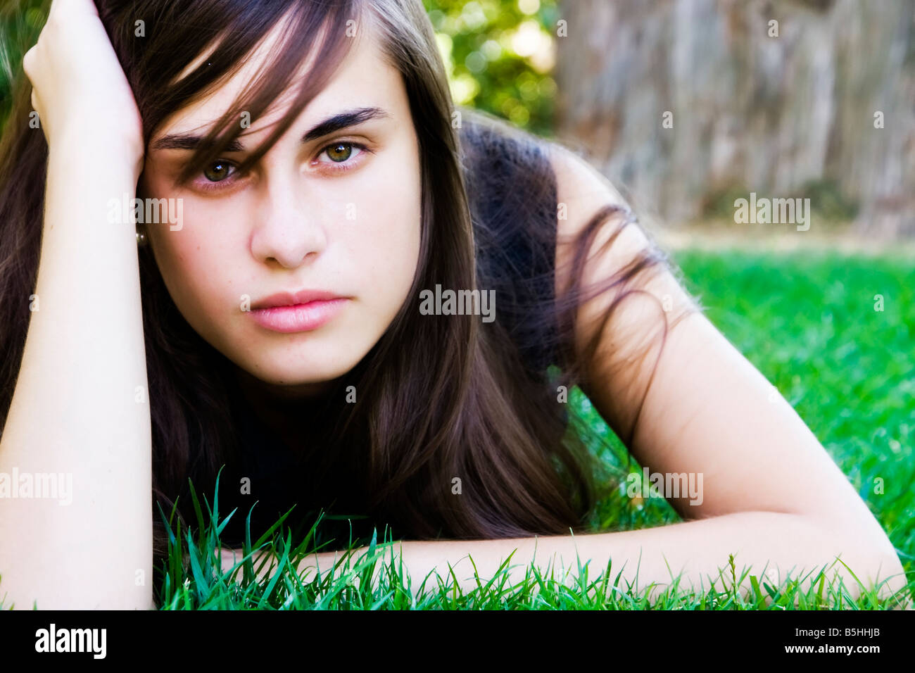 Young staring woman laying on the grass Stock Photo