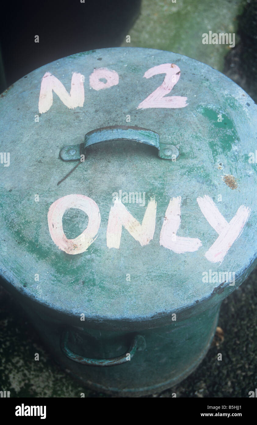 Close up of lid on galvanised iron dustbin standing in backyard and once painted green with fresher pink lettering No 2 ONLY Stock Photo