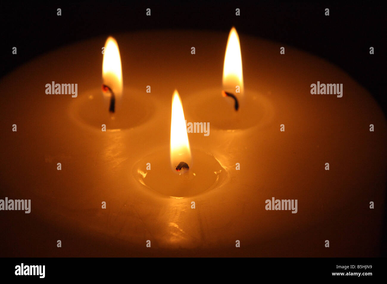 Burning candle with three wicks Stock Photo Alamy
