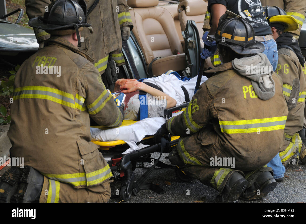 Firefighters remove a man that was trapped in his car after they cut ...