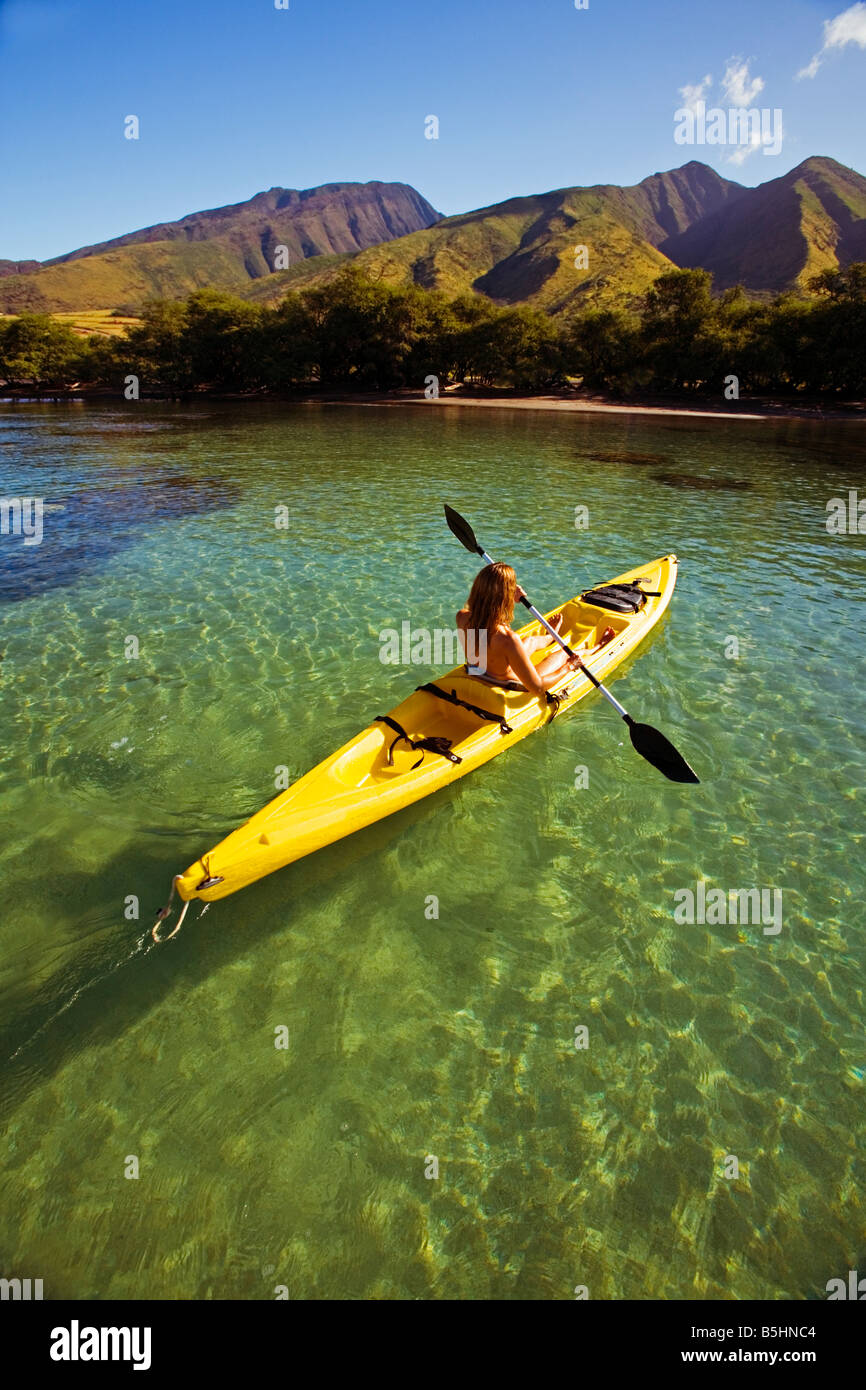 A young woman paddles a kayak at Olowalu, Maui, Hawaii. Stock Photo
