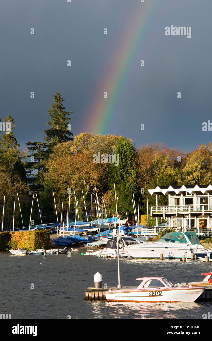 Boats moored at Windermere Lake with rainbow in blue sky. Stock Photo