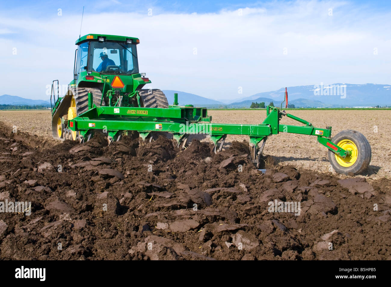 A track tractor pulling a reversible plow turns over the soil as a step