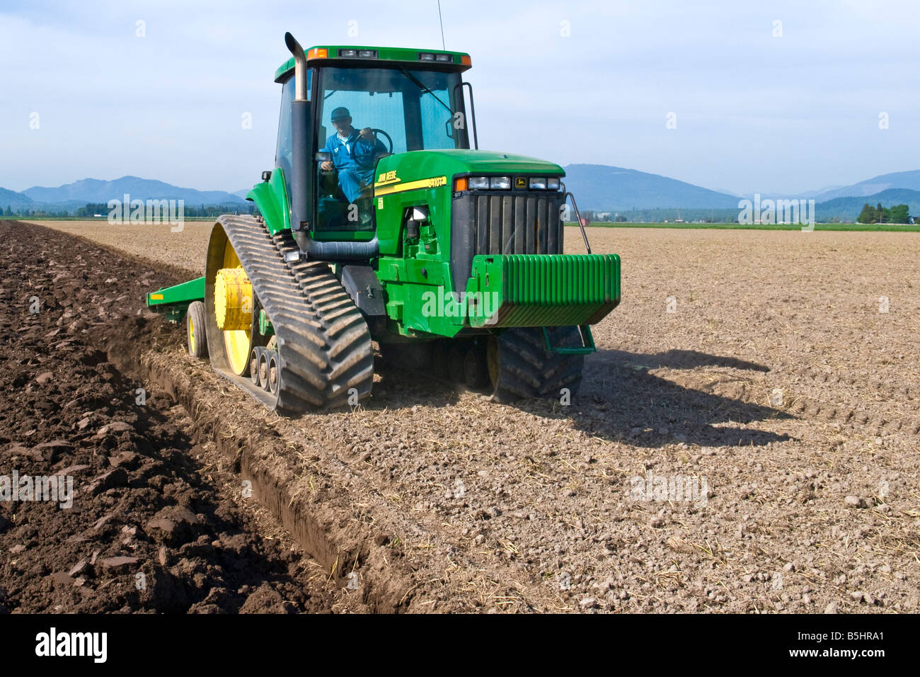 A track tractor pulling a reversible plow turns over the soil as a step
