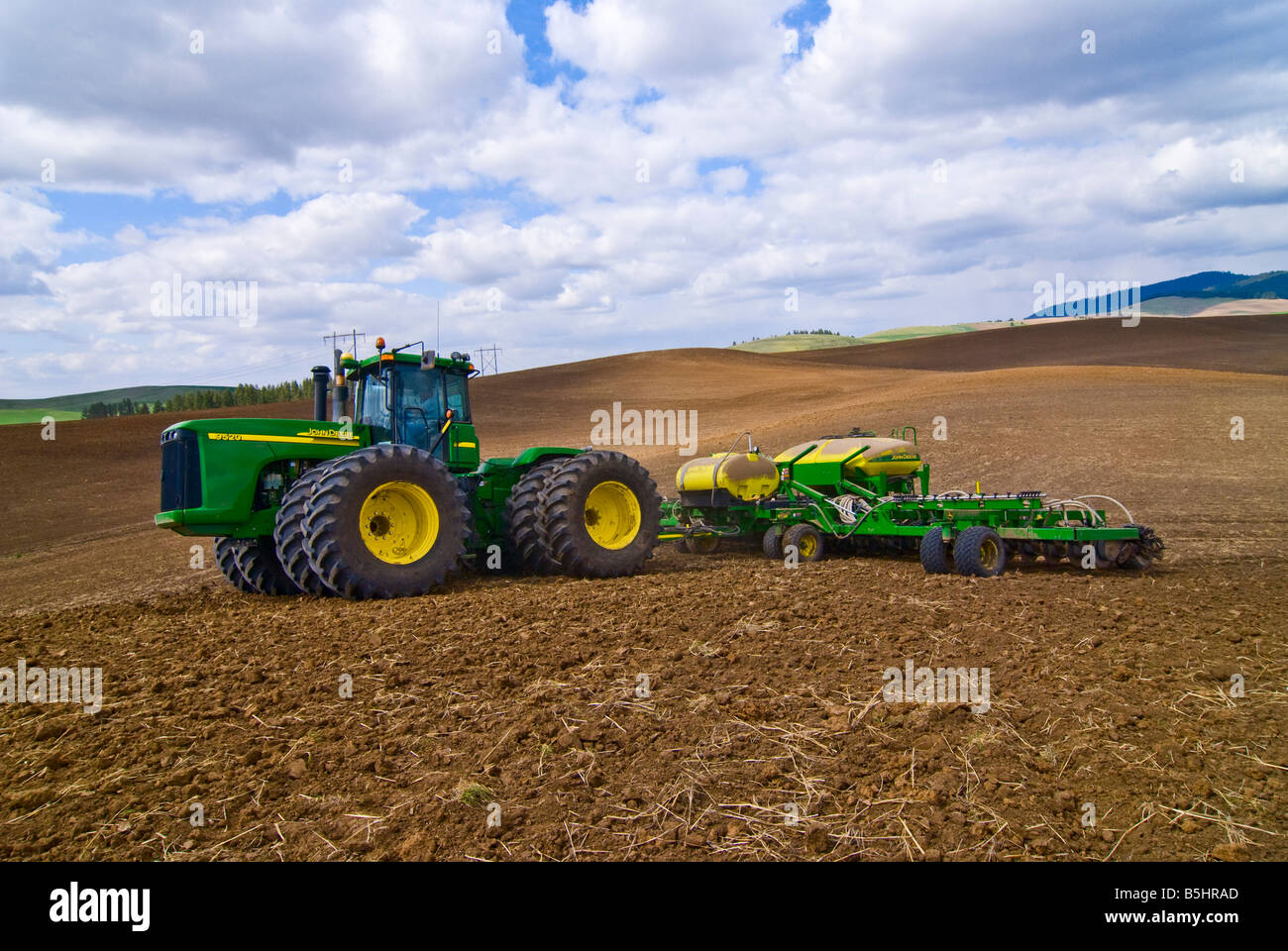 A tractor pulls an air seeder to plant grains or legumes in the spring