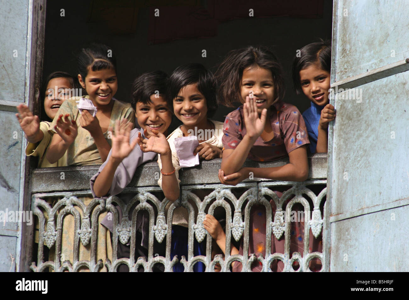Children waving from schoolroom window Jaipur India Stock Photo