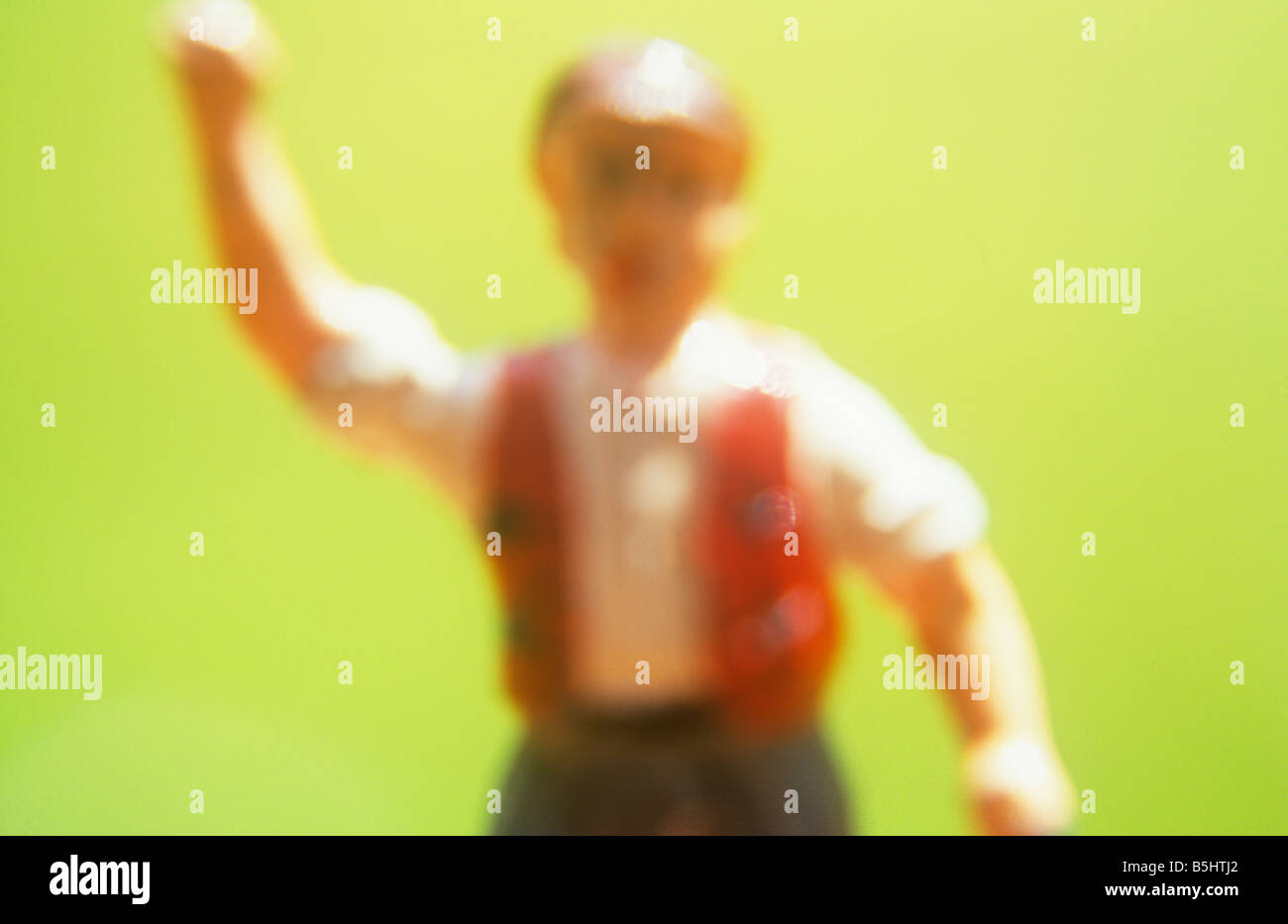 Impressionistic close up of model of farmworker or manual labourer shaking his fist and shouting angrily with grass behind Stock Photo