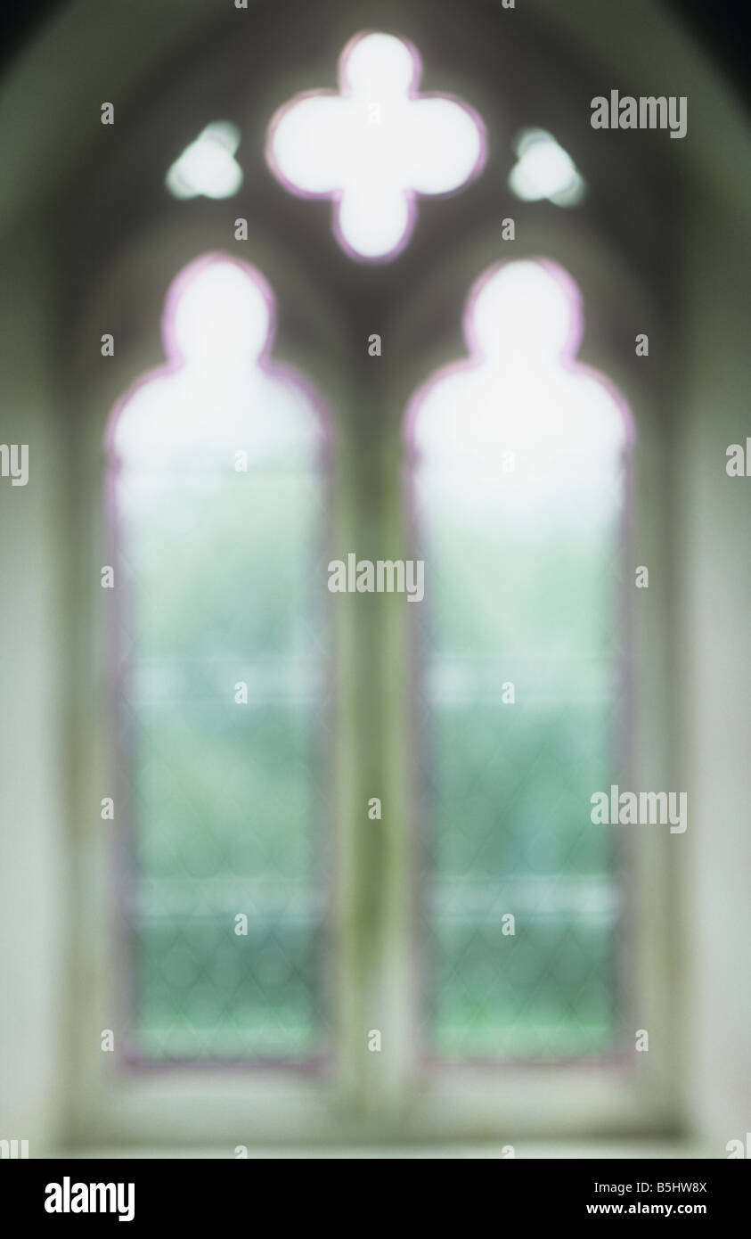 Impressionistic Early English Gothic diamond-leaded plain window with mauve fringes with grass and bushes outside Stock Photo
