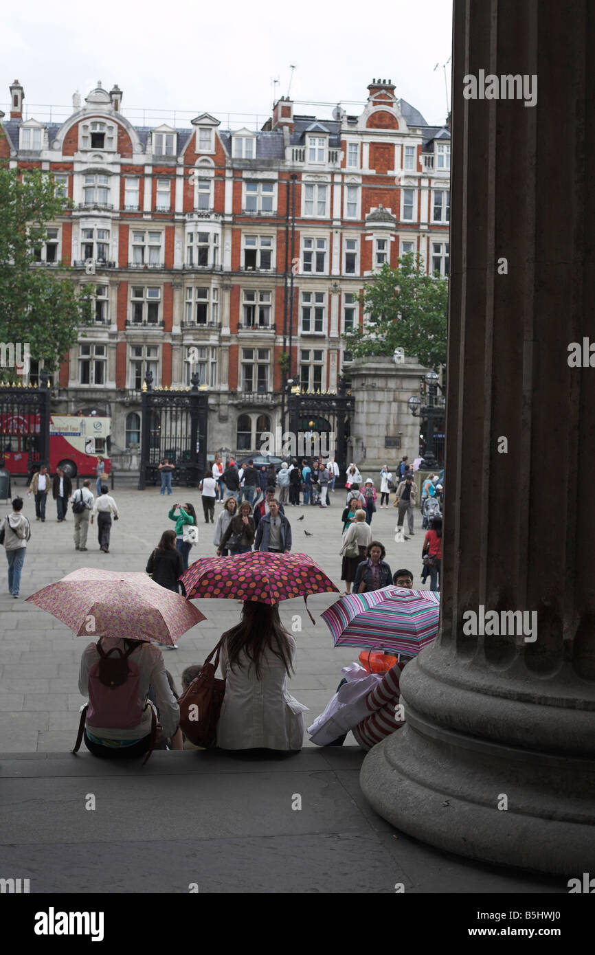 Three woman shelter under umbrellas outside British Museum London Stock Photo