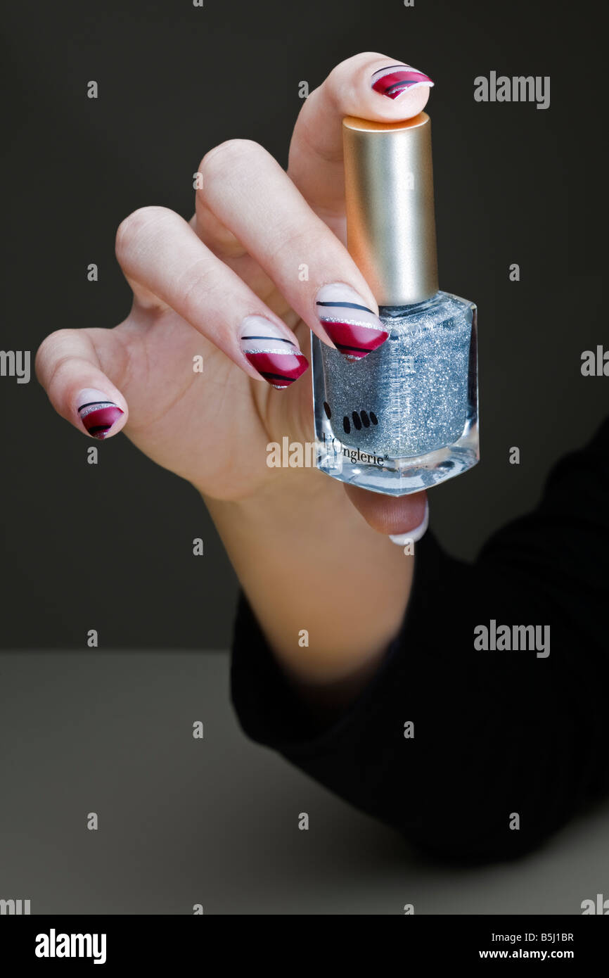 A manicured hand exposing a nail polish bottle. Main manucurée présentant un flacon de vernis à ongles. Stock Photo