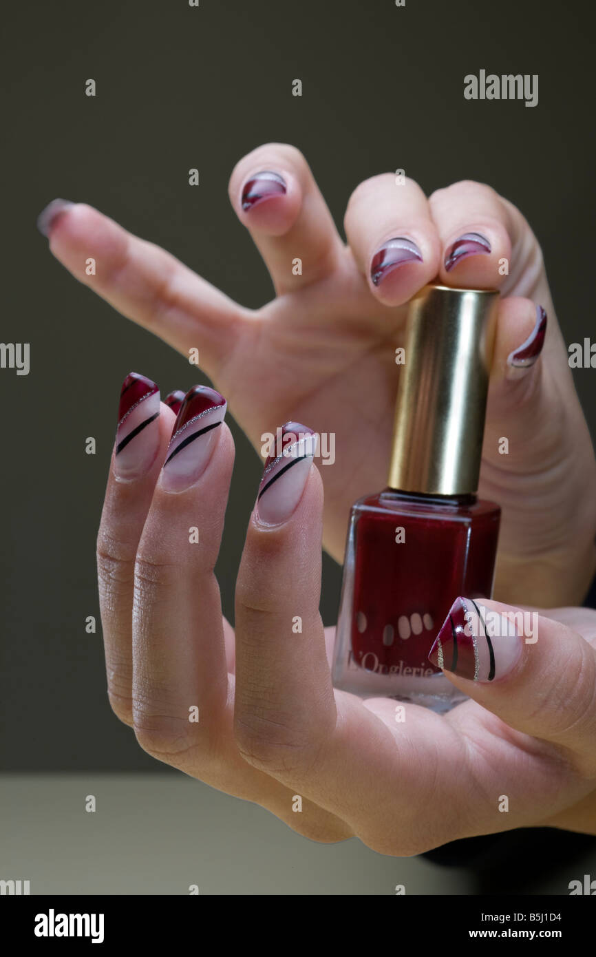 Manicured hands exposing a nail polish bottle. Mains manucurées présentant un flacon de vernis à ongles. Stock Photo
