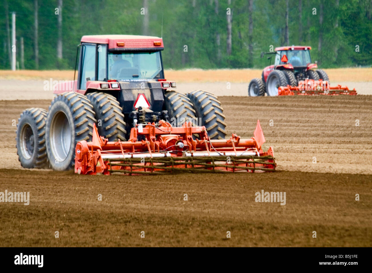 A pair of tractors rototilling a seedbed prior to planting potatoes in