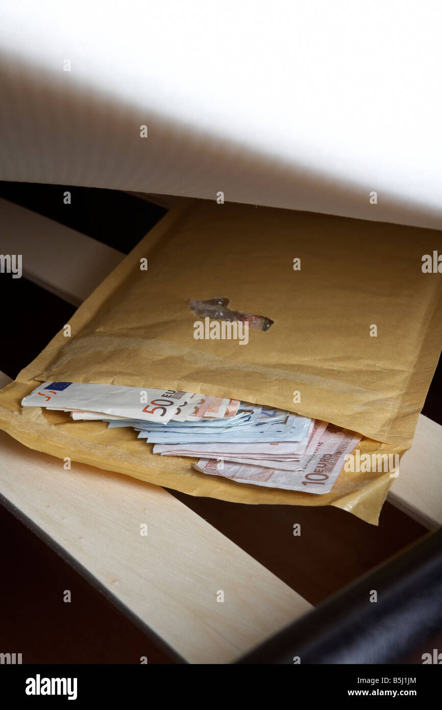 wad of 50 20 and 10 euro notes cash in an envelope stuffed under the mattress of a bed Stock Photo
